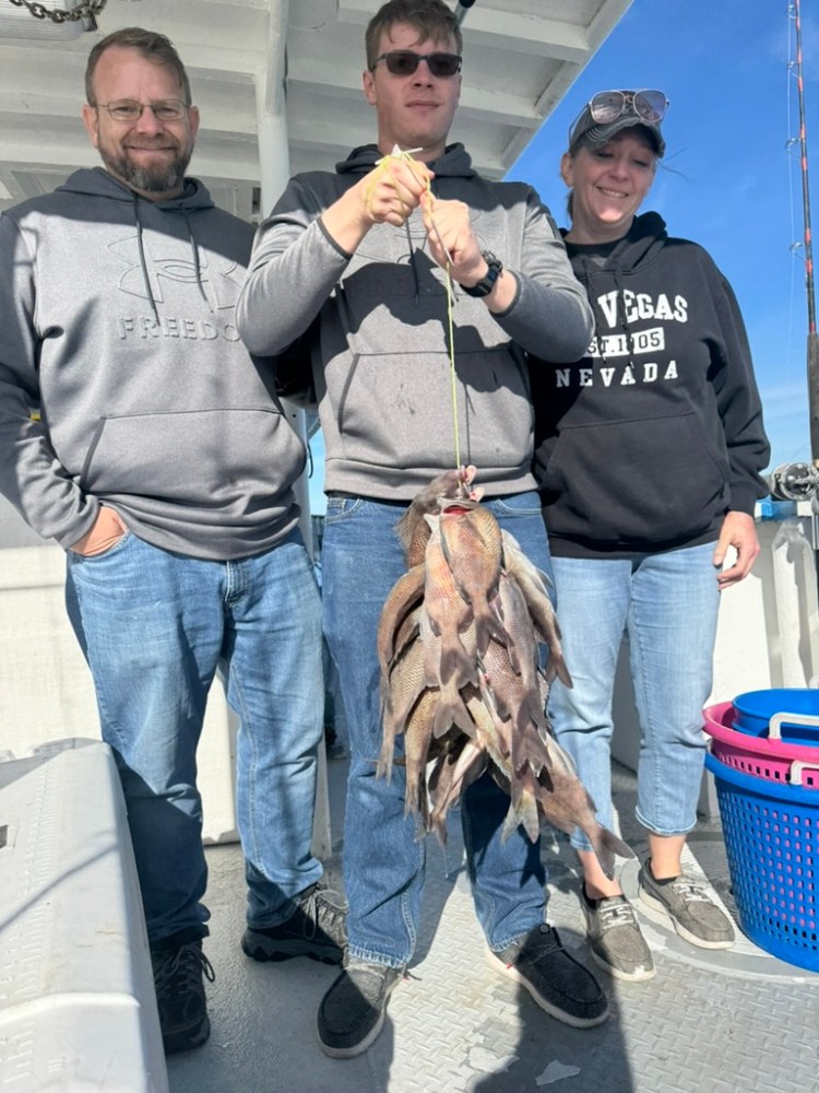 a group of people standing next to a man holding a fish